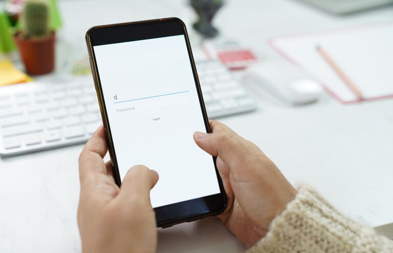 Woman hand typing Mobile phone to login account and password on Facebook webpage to connect with friends at Desk office