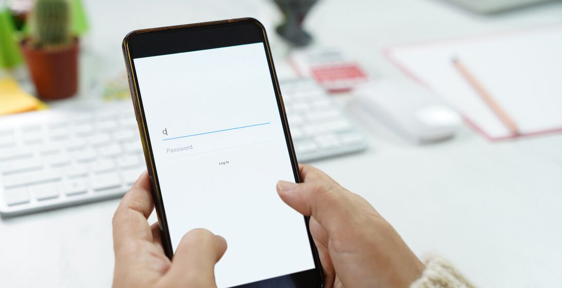 Woman hand typing Mobile phone to login account and password on Facebook webpage to connect with friends at Desk office