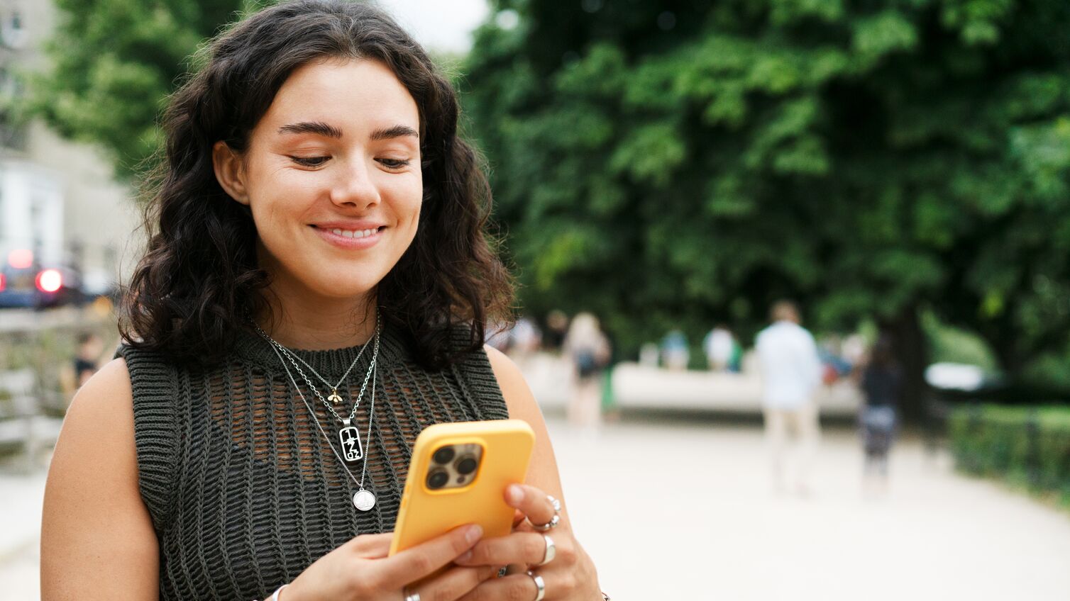 Woman wearing a knitted short sleeved top using her phone with a bright yellow case