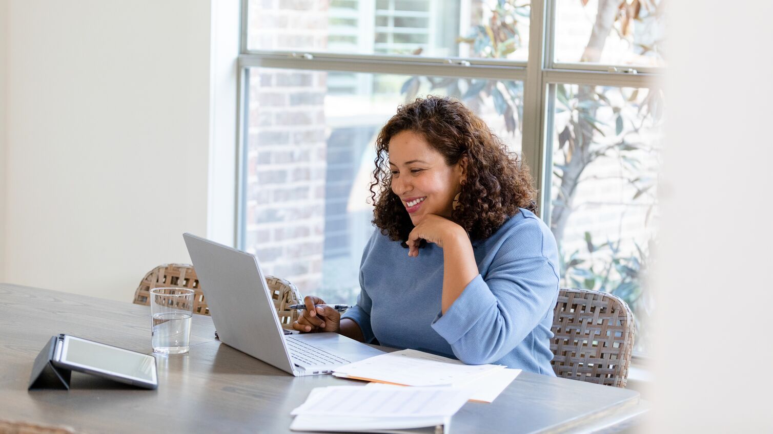The small business owner smiles while attending a virtual meeting with her financial advisor to review upcoming changes to her taxes.