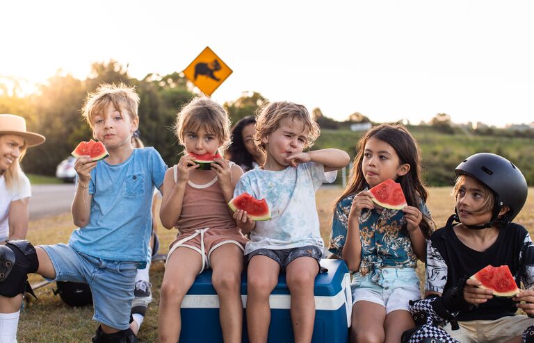 Aussie and mums and their kids eat watermelon under a koala sign