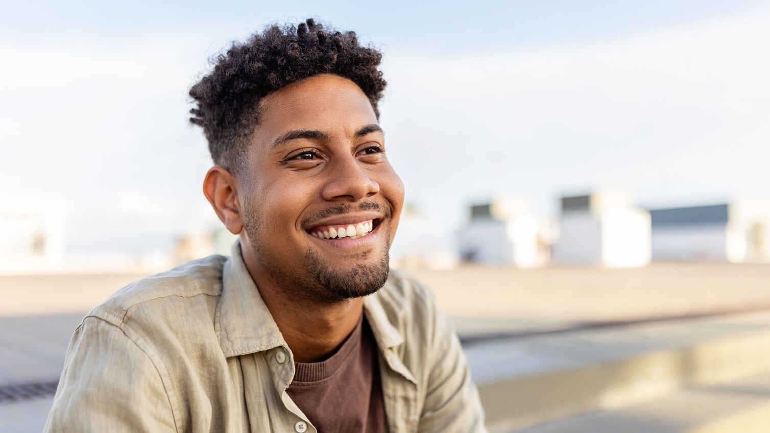 Portrait of young smiling african american man sitting outdoors. Happy people concept.