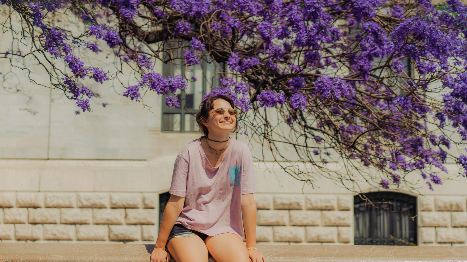 Girl sitting under purple flowers