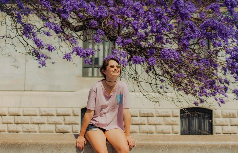 Girl sitting under purple flowers
