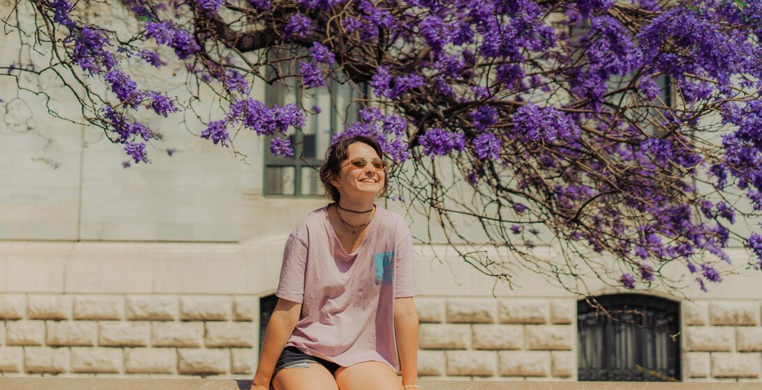 Girl sitting under purple flowers