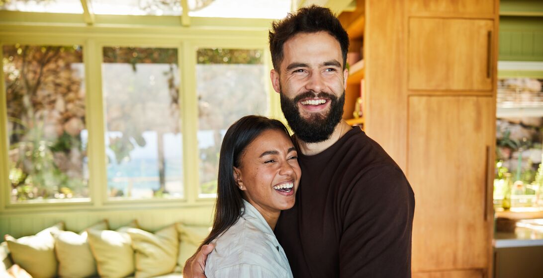 Couple standing in their dining room hugging and smiling
