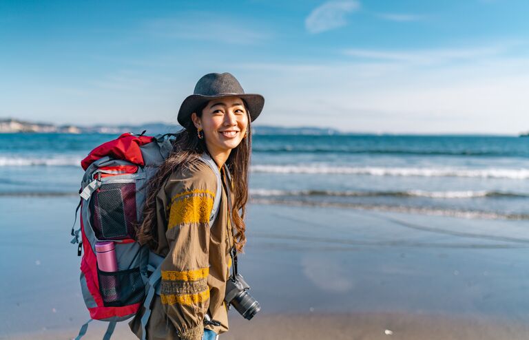 A young female traveller is enjoying spending time at the beach on her vacation.