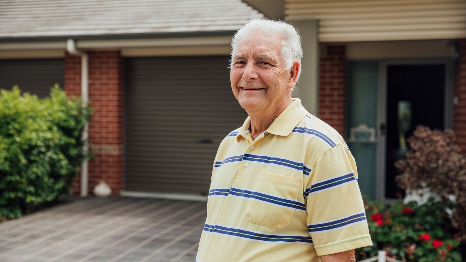 A shot of a senior caucasian man standing outdoors in a residential district.