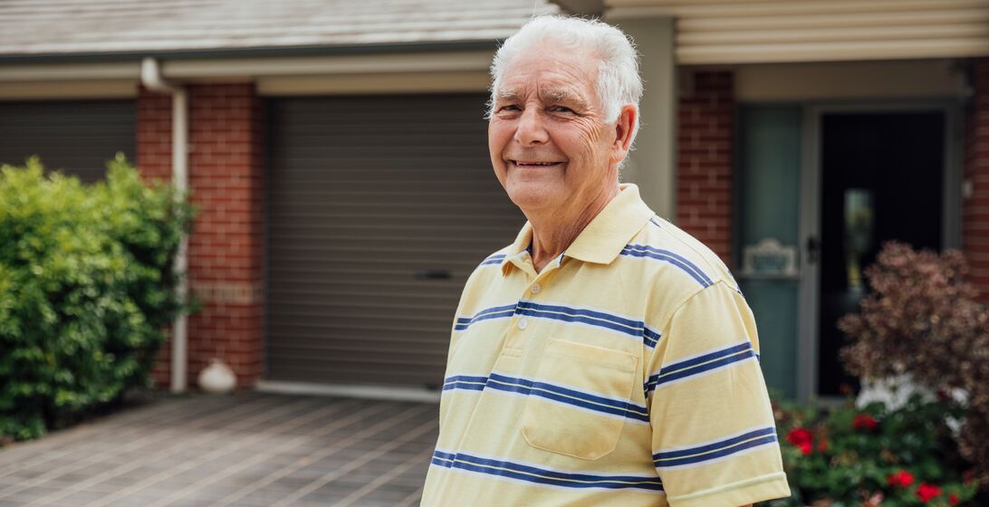 A shot of a senior caucasian man standing outdoors in a residential district.