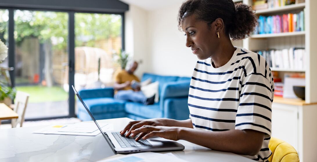 Happy black woman working at home using her laptop computer - telecommuting concepts