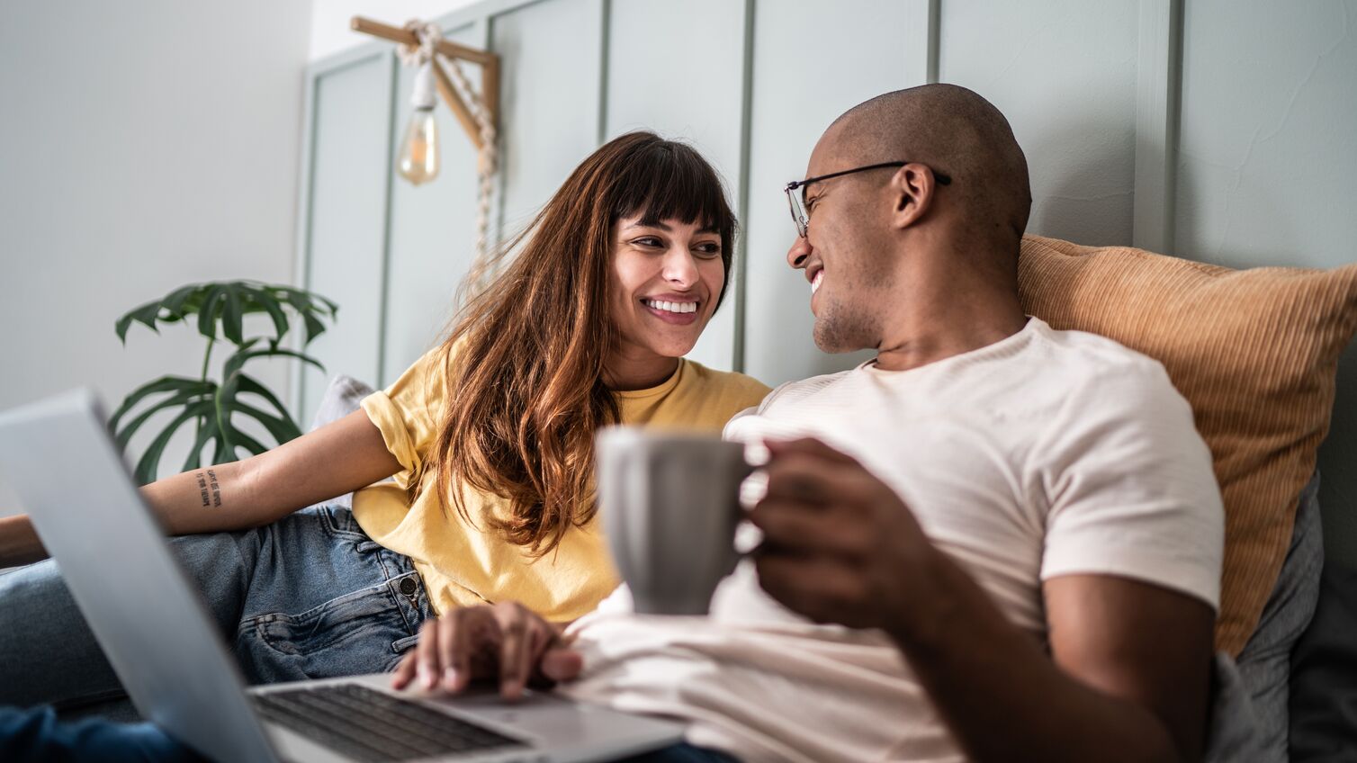 Young couple using the laptop in the bed at home