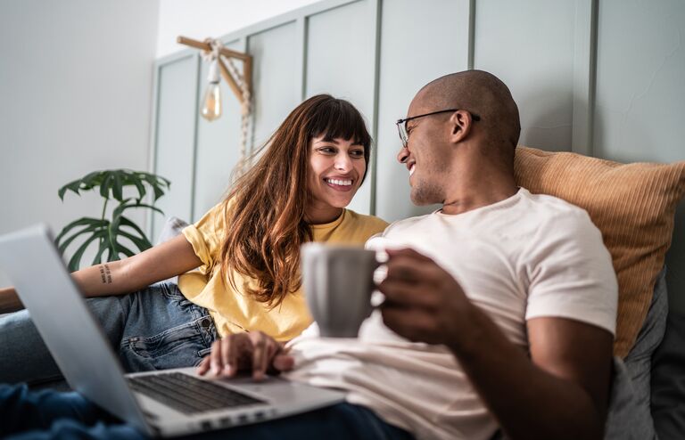 Young couple using the laptop in the bed at home