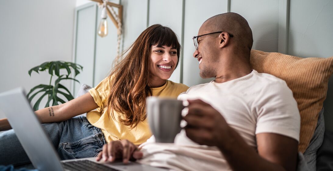 Young couple using the laptop in the bed at home