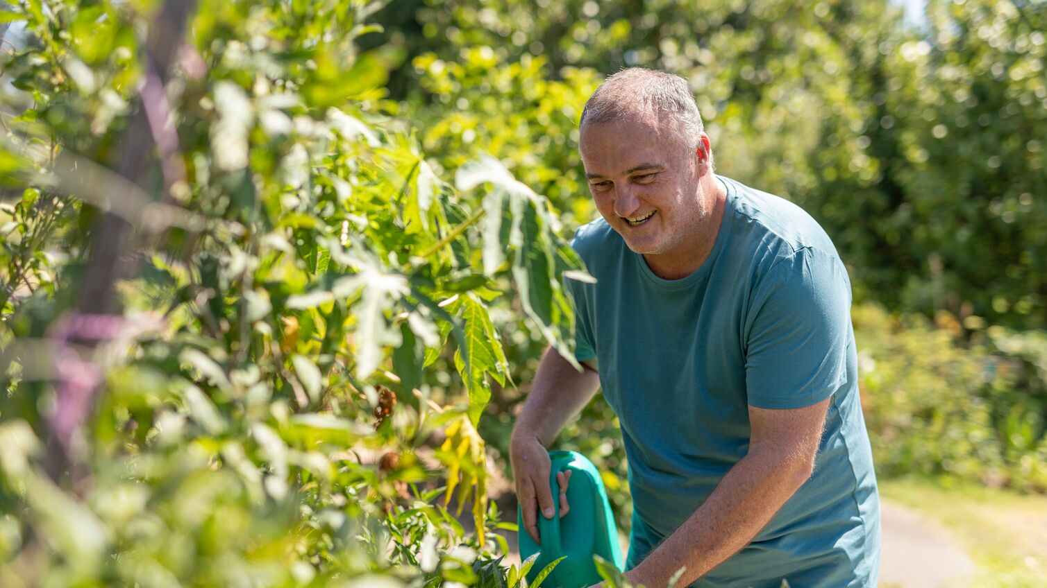 Man watering plants in a community vegetable garden