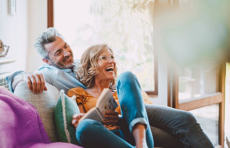 Cheerful mature couple sitting on sofa at home