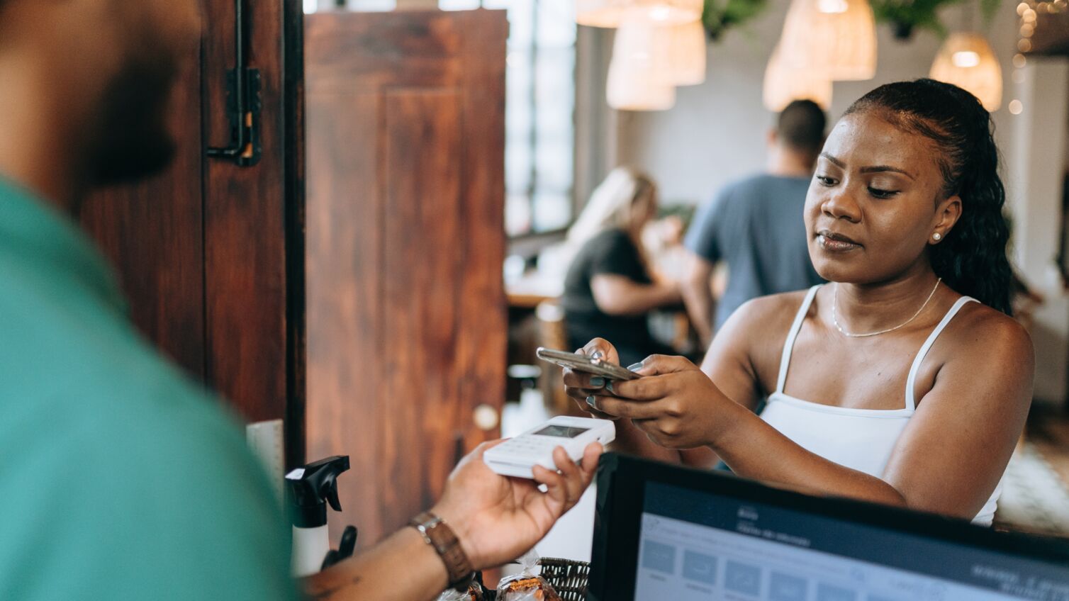 Female customer at a restaurant paying for their meal with their mobile wallet