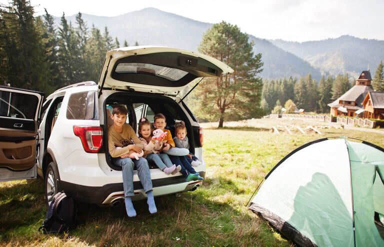 Family of four kids at vehicle interior. Children sitting in trunk. Traveling by car in the mountains, atmosphere concept.