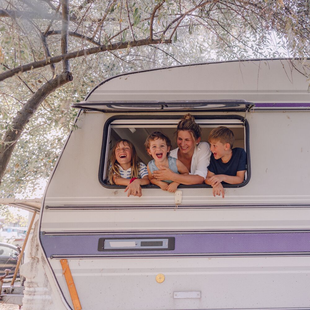 Photo of smiling mother and her children in their camper van during vacation
