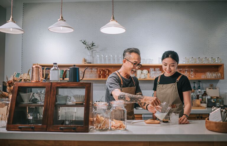 asian chinese senior male barista teaching his daughter making coffee at cafe counter