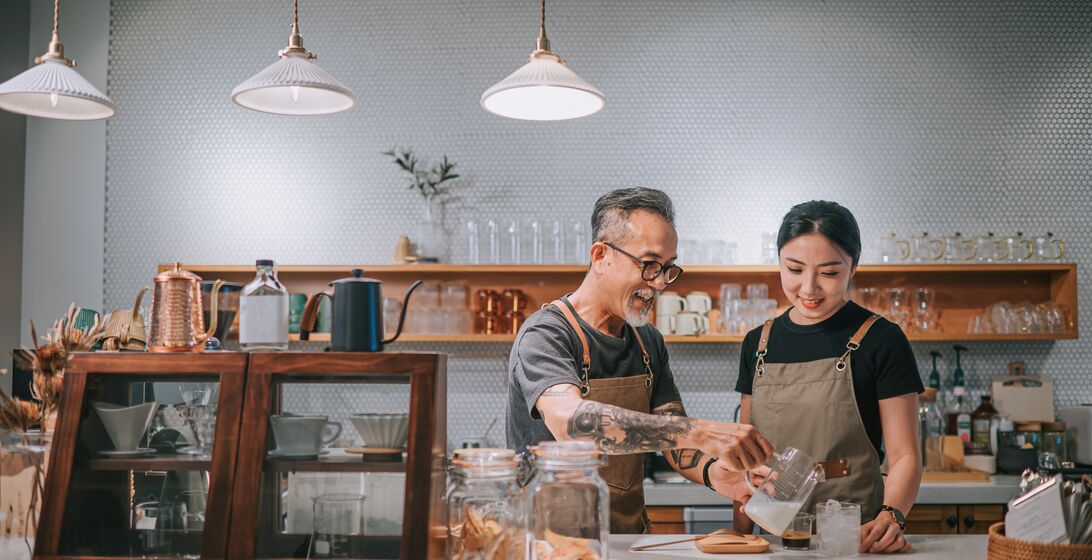 asian chinese senior male barista teaching his daughter making coffee at cafe counter