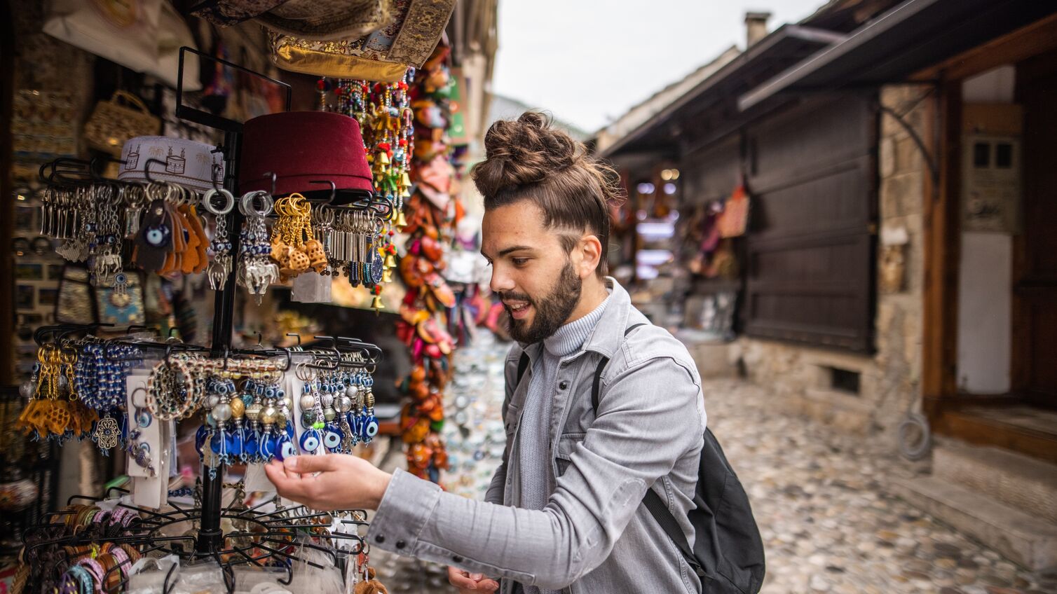 Young male tourist with backpack looking for souvenirs in local street market