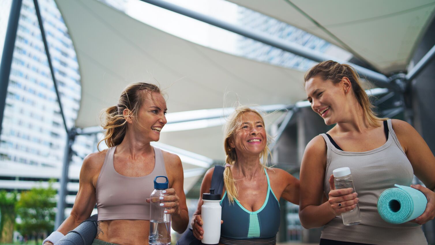 A group of young and old women walking after exercise outdoors in city, talking.