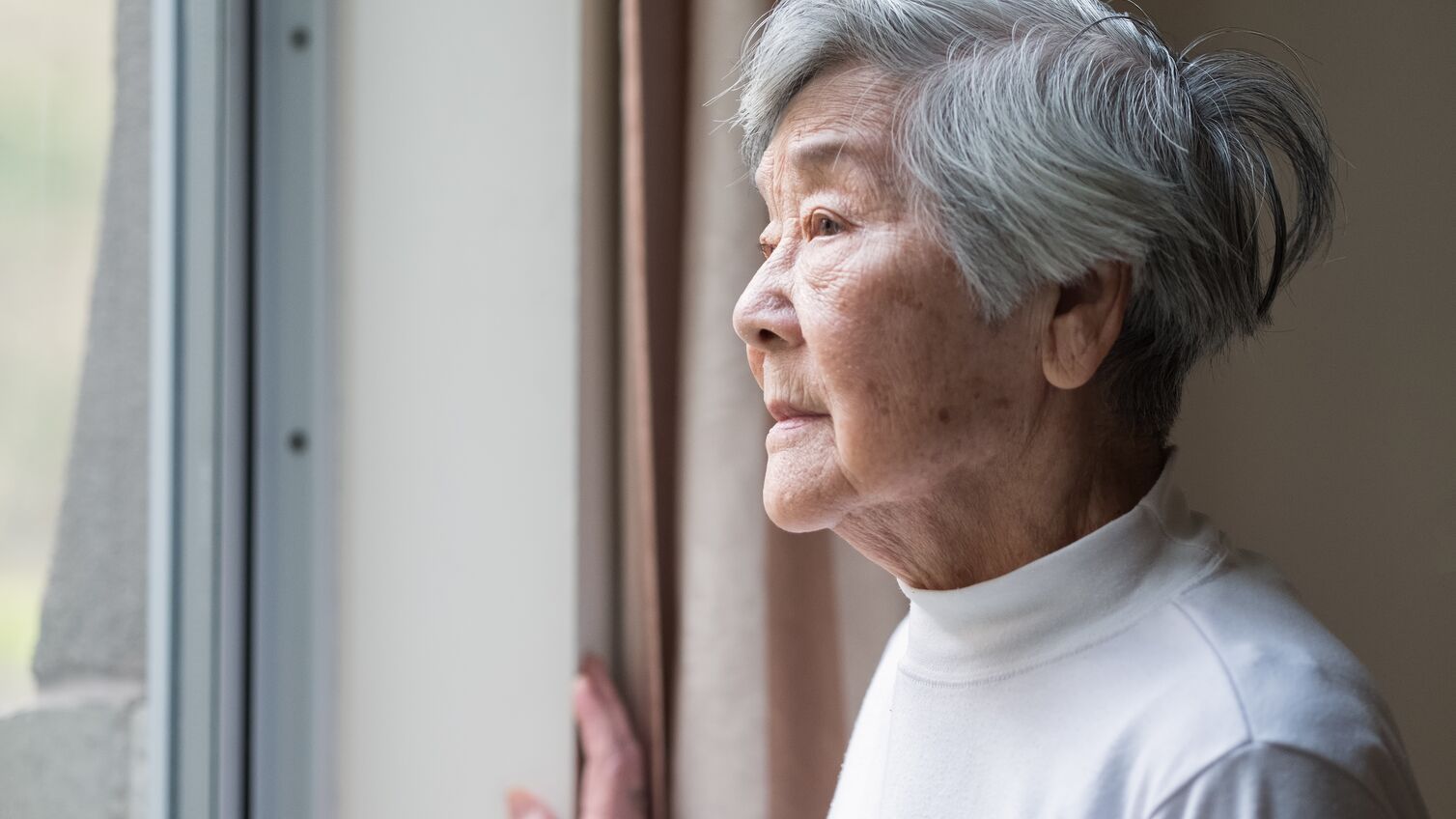 Chinese senior woman looking outside.