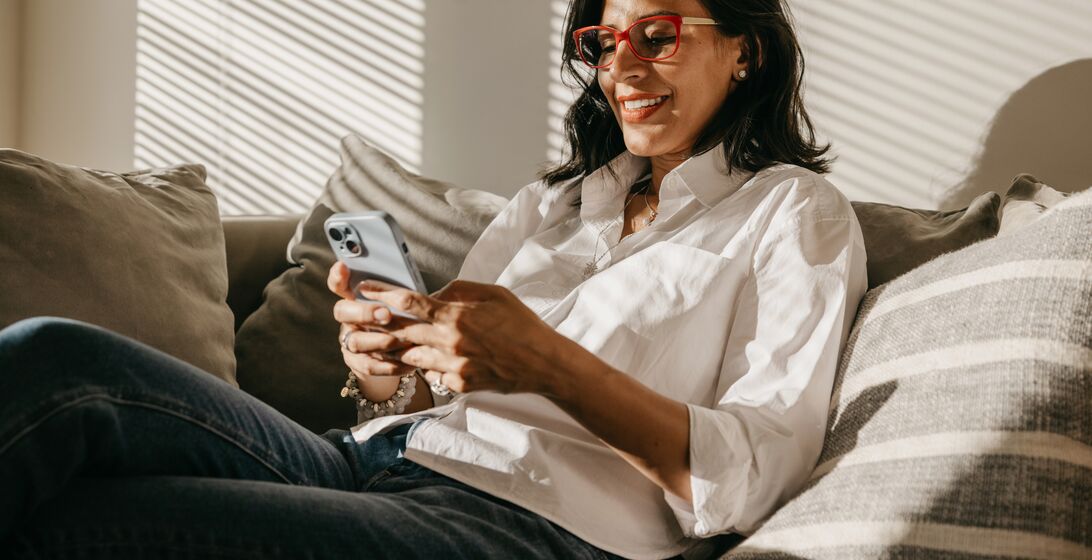 Latin woman from her house in New York relaxing and chatting on mobile with a beautiful sunlight coming in from the side window.