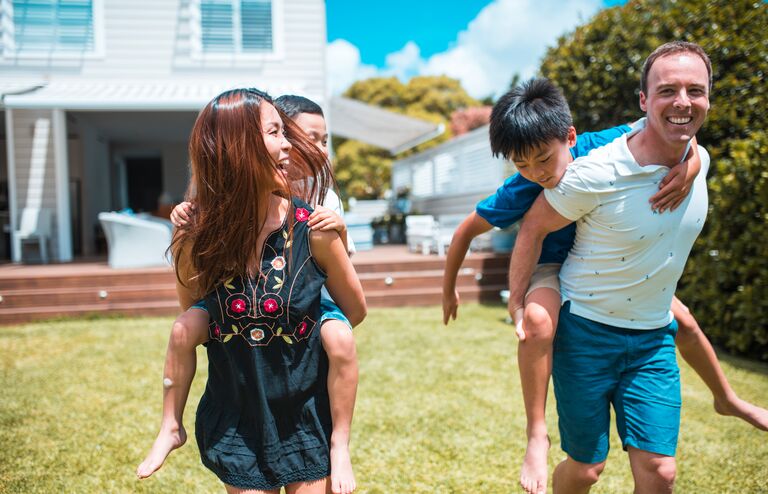 Mother and father holding their sons in piggyback position. They are having fun.