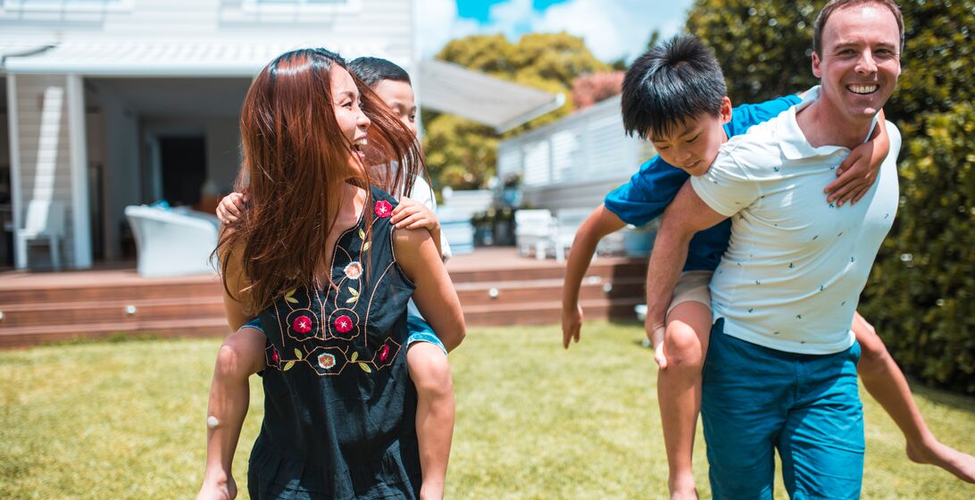 Mother and father holding their sons in piggyback position. They are having fun.