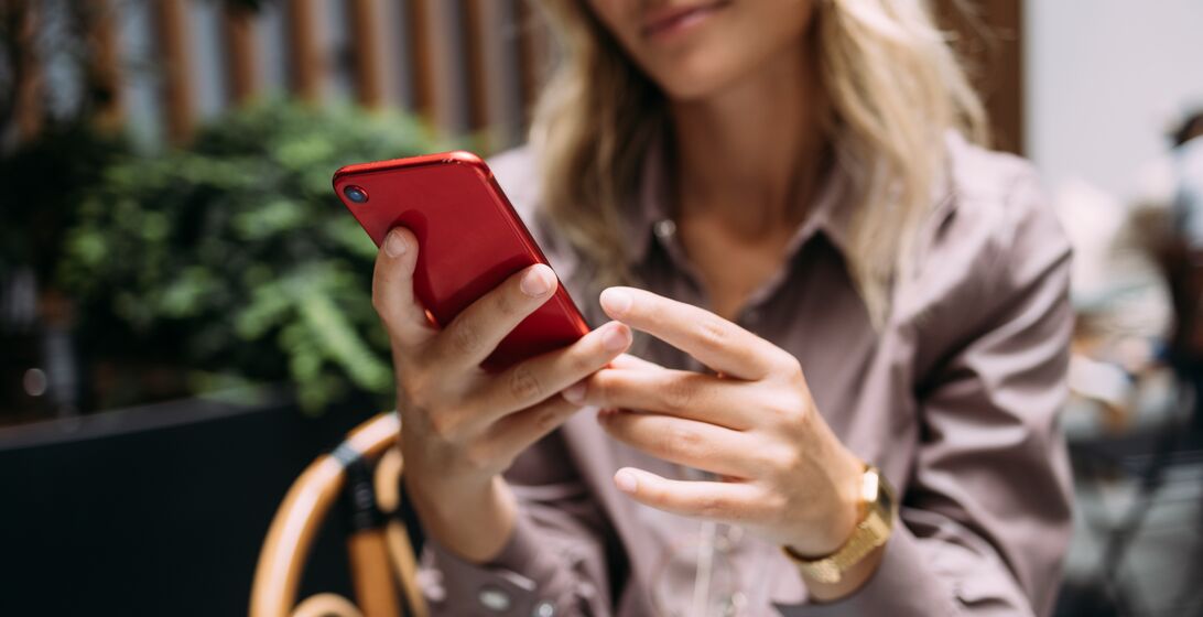 An anonymous business woman typing text message on her smartphone while sitting in a coffee shop