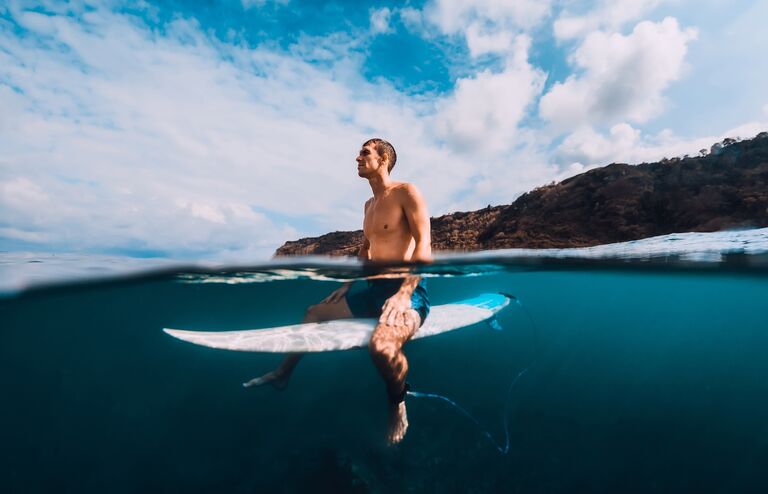 Surfer man with surfboard relaxing at line up in ocean