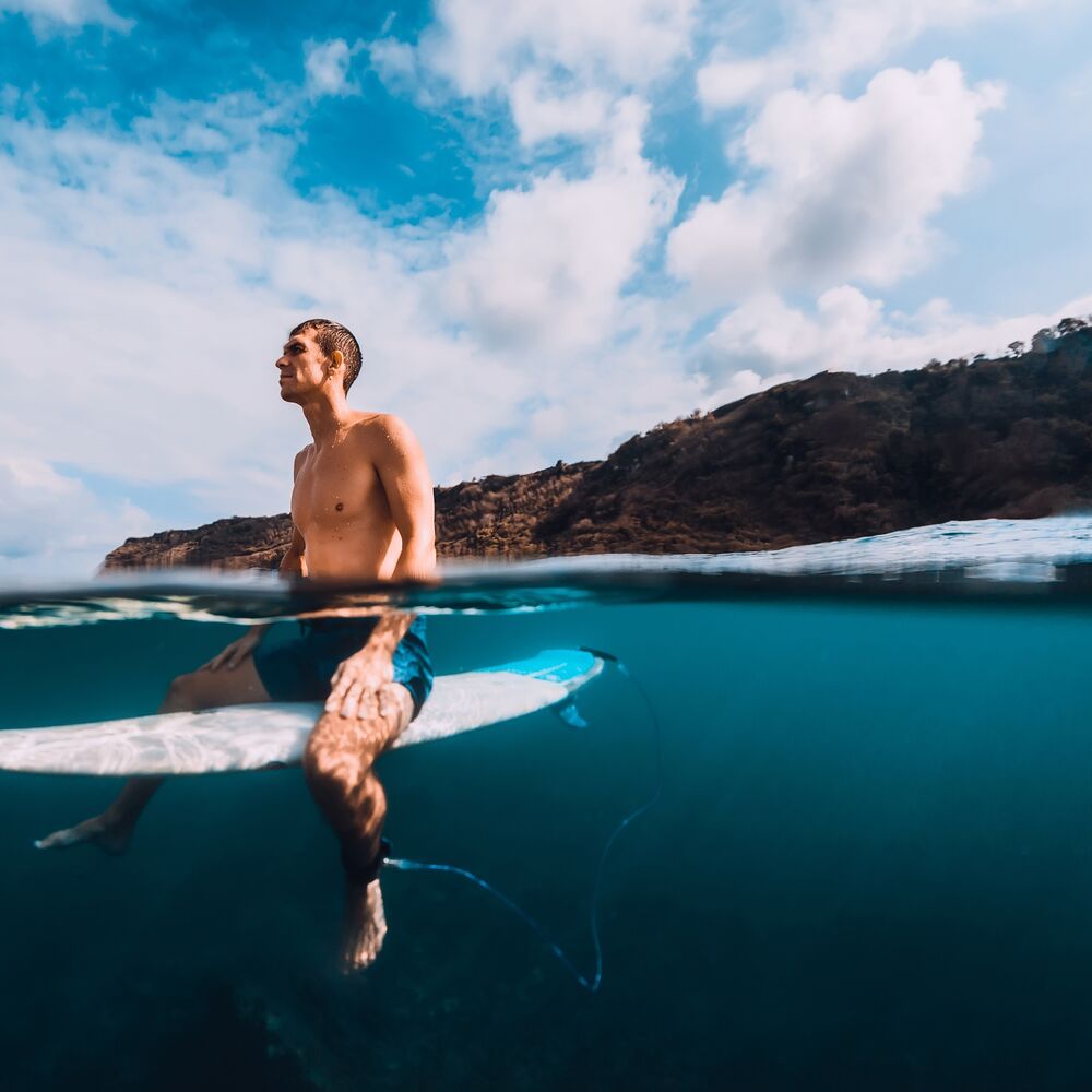 Surfer man with surfboard relaxing at line up in ocean