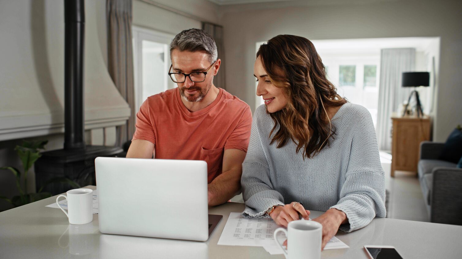 A husband and wife looking at their laptop in their kitchen