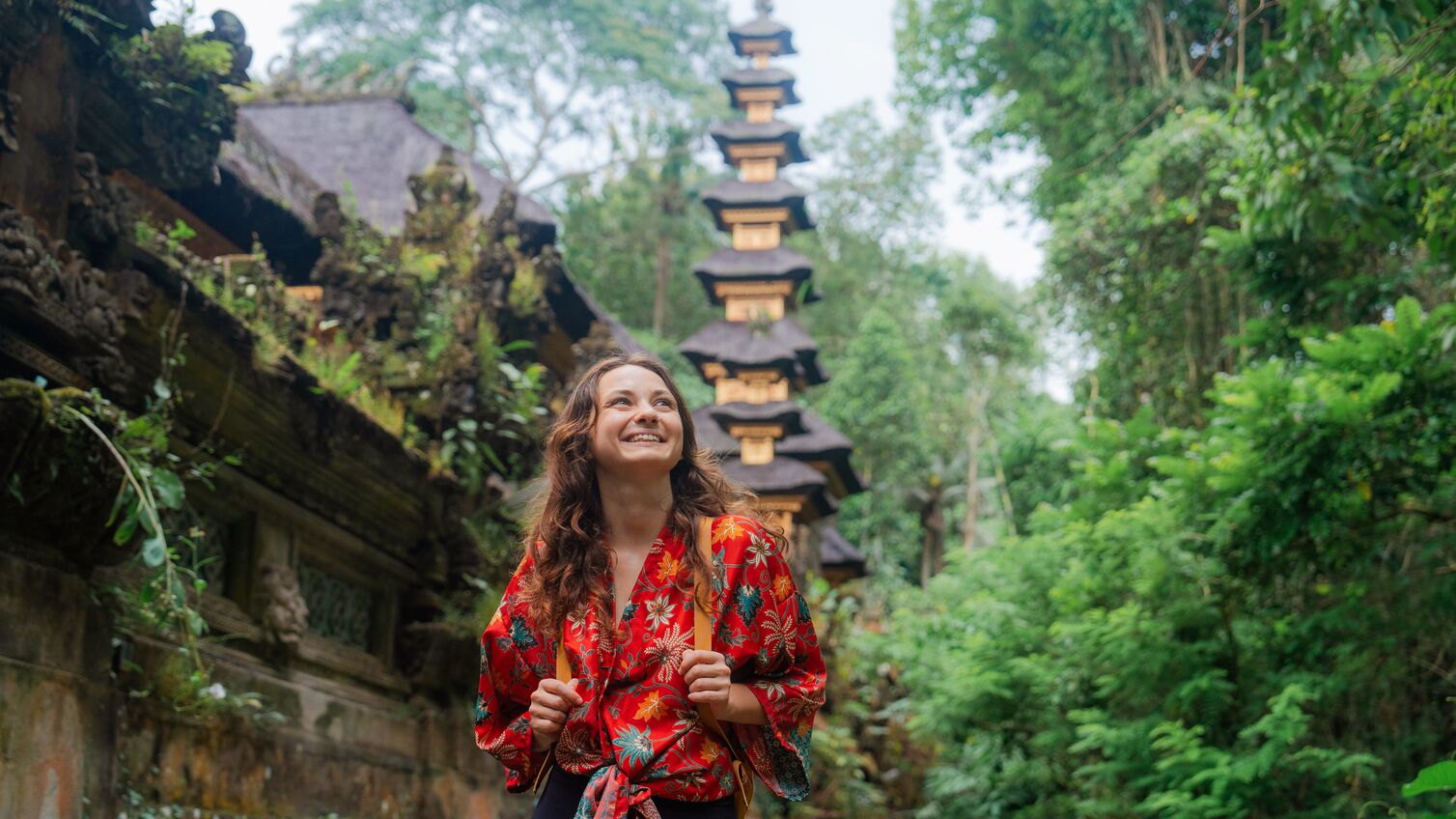 Woman walking past the temple in the jungles in Ubud, Bali