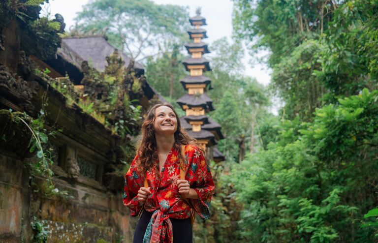 Woman walking past the temple in the jungles in Ubud, Bali