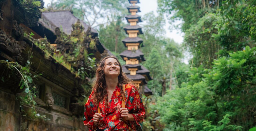 Woman walking past the temple in the jungles in Ubud, Bali