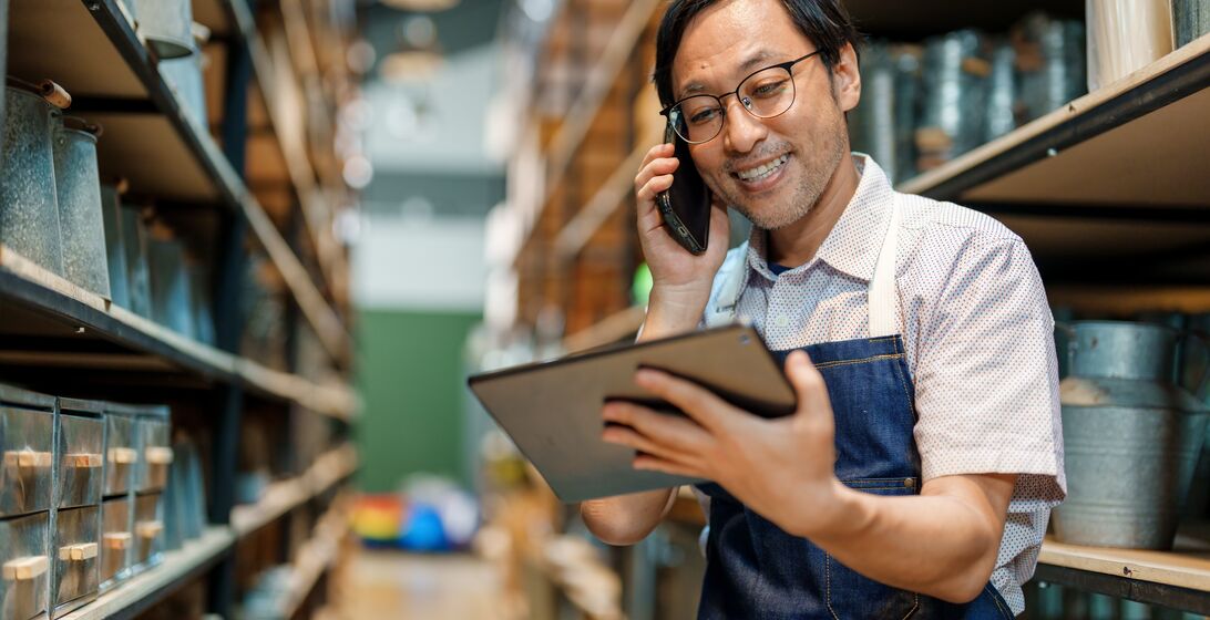 Japanese man shop owner in his store warehouse using mobile phone and tablet confirm online order received correctly with customer. Small business owner at work. Small business local craft product. Online shopping concept.