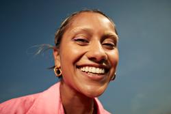 Close-up portrait of happy young woman with toothy smile against sky