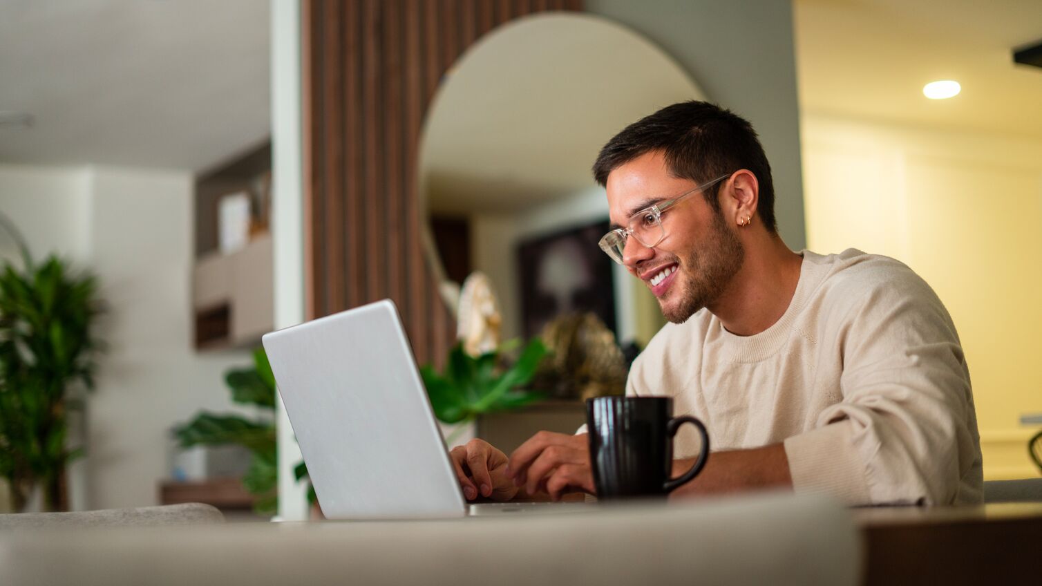 Latino ethnic man between the ages of 25-35 is using his laptop to surf the internet at home