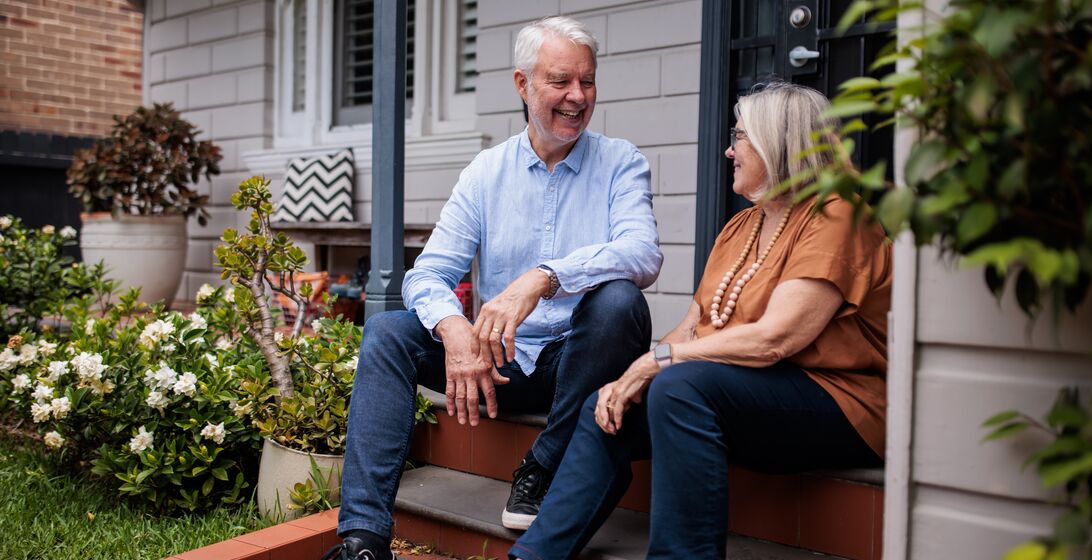 Senior couple sitting on the steps of their home