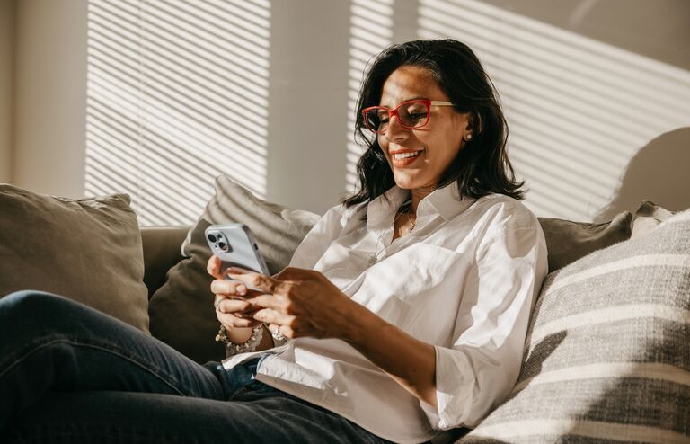 Latin woman from her house in New York relaxing and chatting on mobile with a beautiful sunlight coming in from the side window.