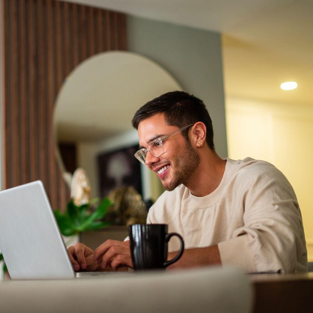 Latino ethnic man between the ages of 25-35 is using his laptop to surf the internet at home