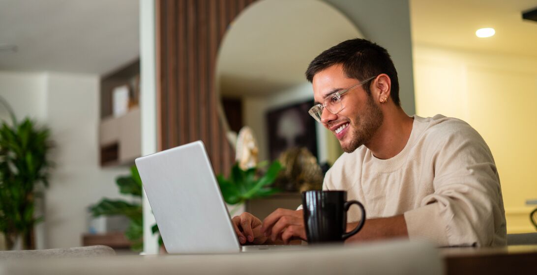 Latino ethnic man between the ages of 25-35 is using his laptop to surf the internet at home