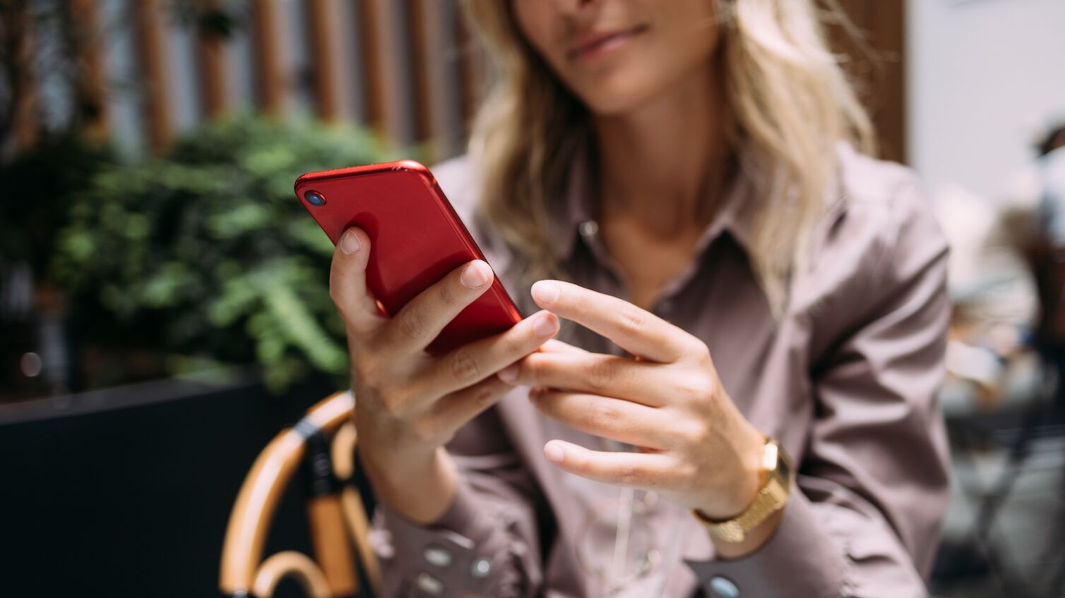 An anonymous business woman typing text message on her smartphone while sitting in a coffee shop