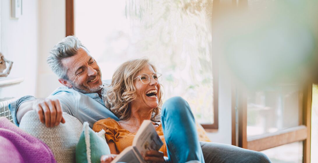 Cheerful mature couple sitting on sofa at home