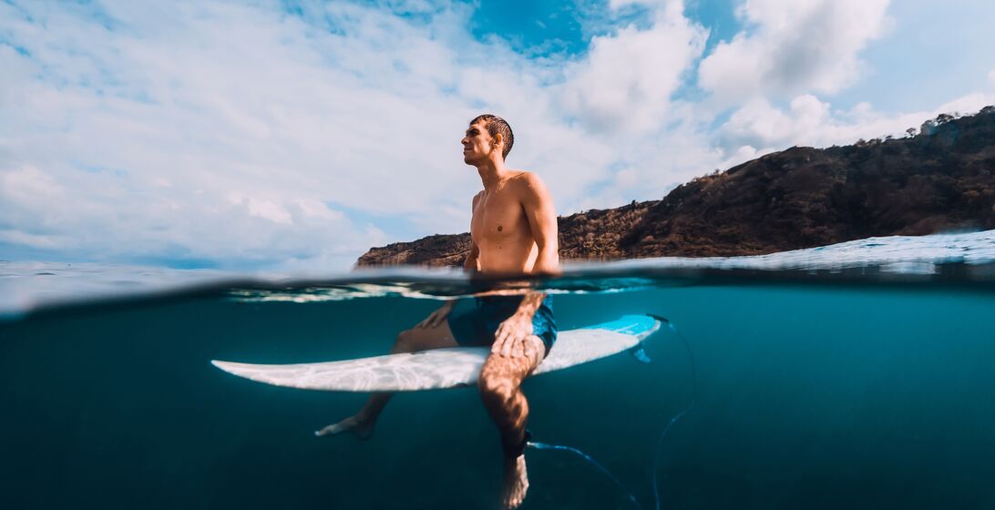 Surfer man with surfboard relaxing at line up in ocean