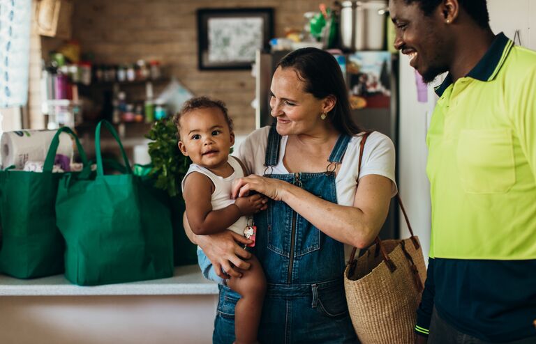 Portrait of a real life young Australian mixed race family in their kitchen with reusable shopping bags in the background