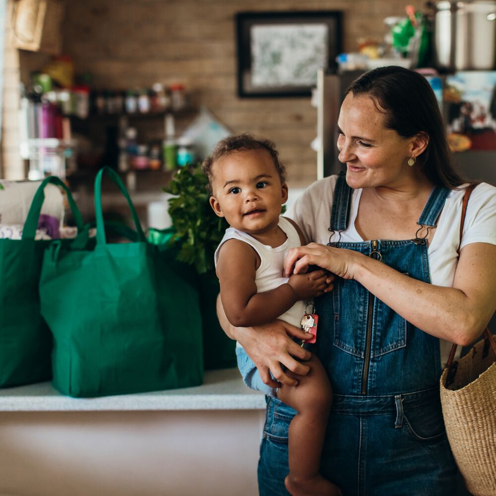 Portrait of a real life young Australian mixed race family in their kitchen with reusable shopping bags in the background