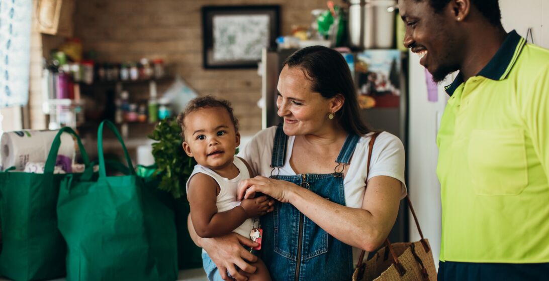 Portrait of a real life young Australian mixed race family in their kitchen with reusable shopping bags in the background